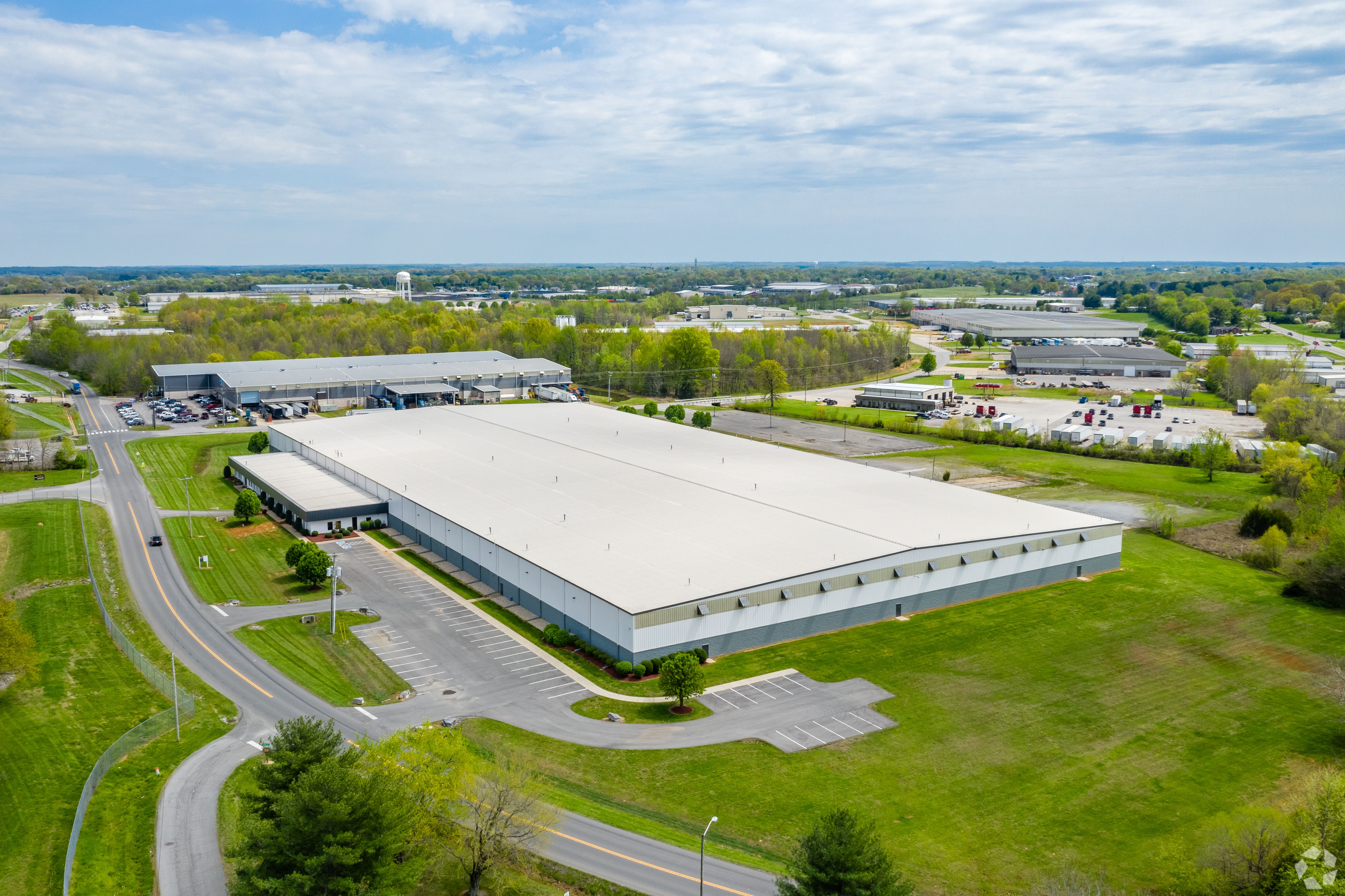 an aerial view shows the large Kirby industrial building. It is white, with lots of green grass surrounding.
