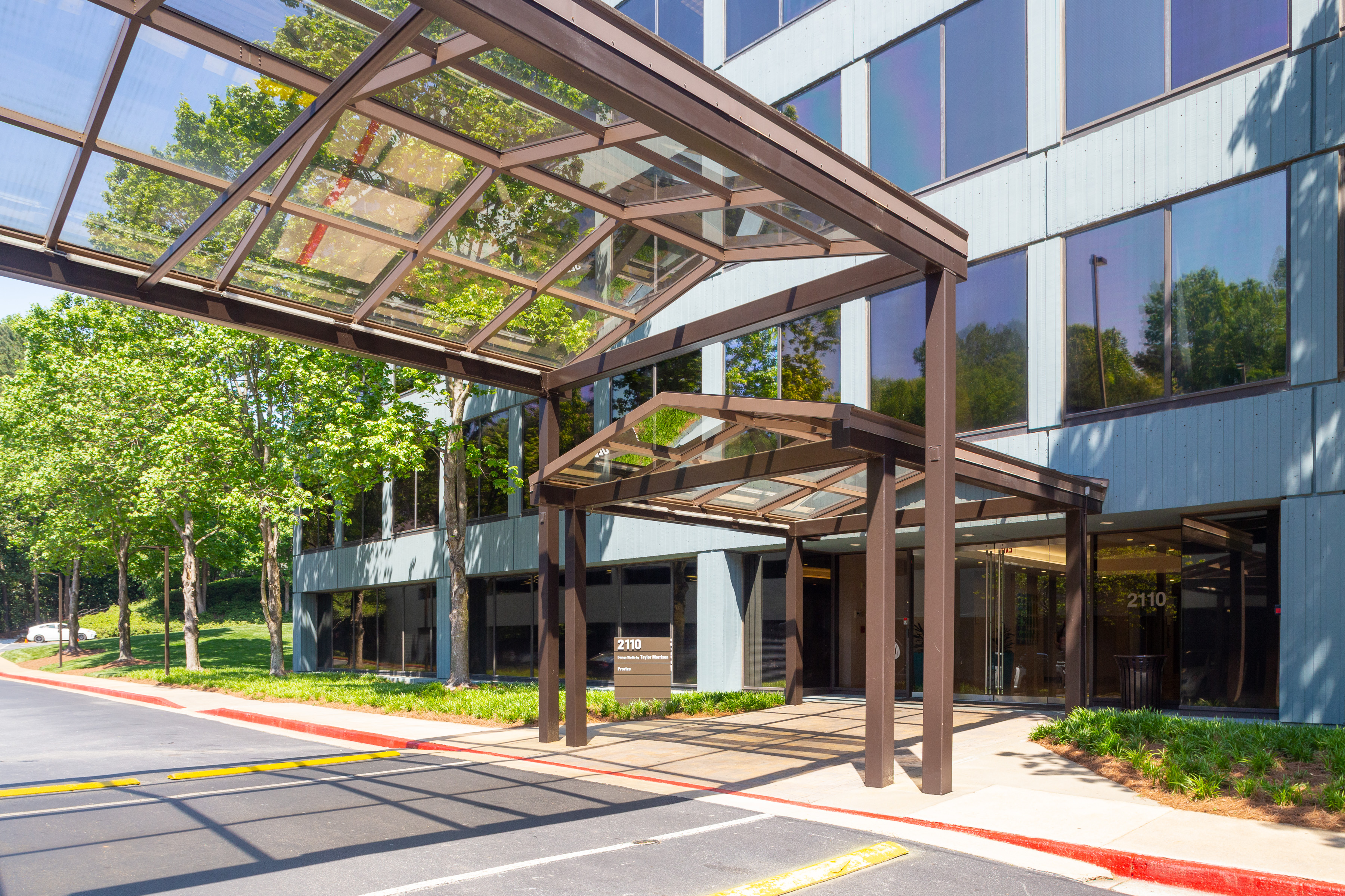 Brown and glass overhead structures form a walkway from the Shadowood office building to the parking lot