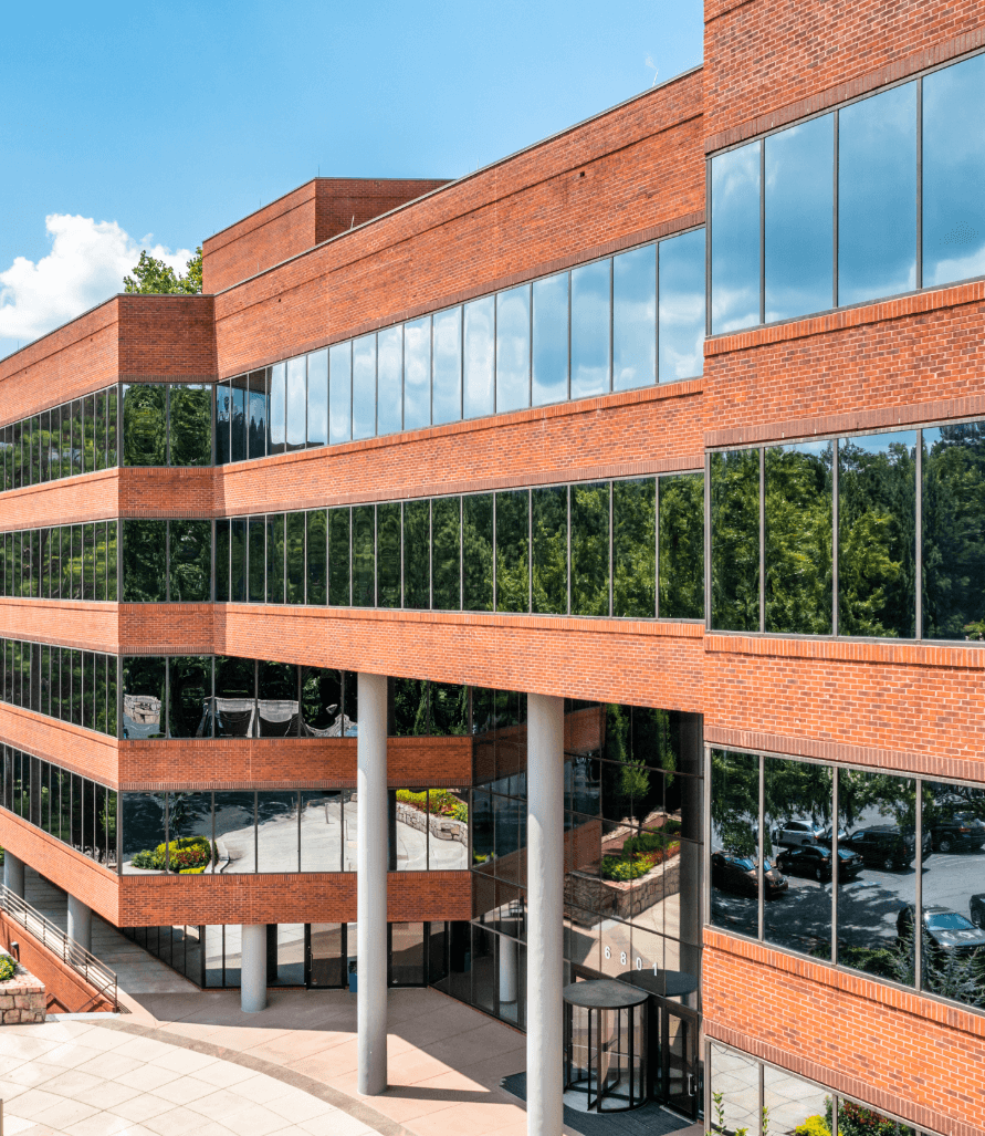 Trees and sky reflecting off the windows of Governor's park red brick office building