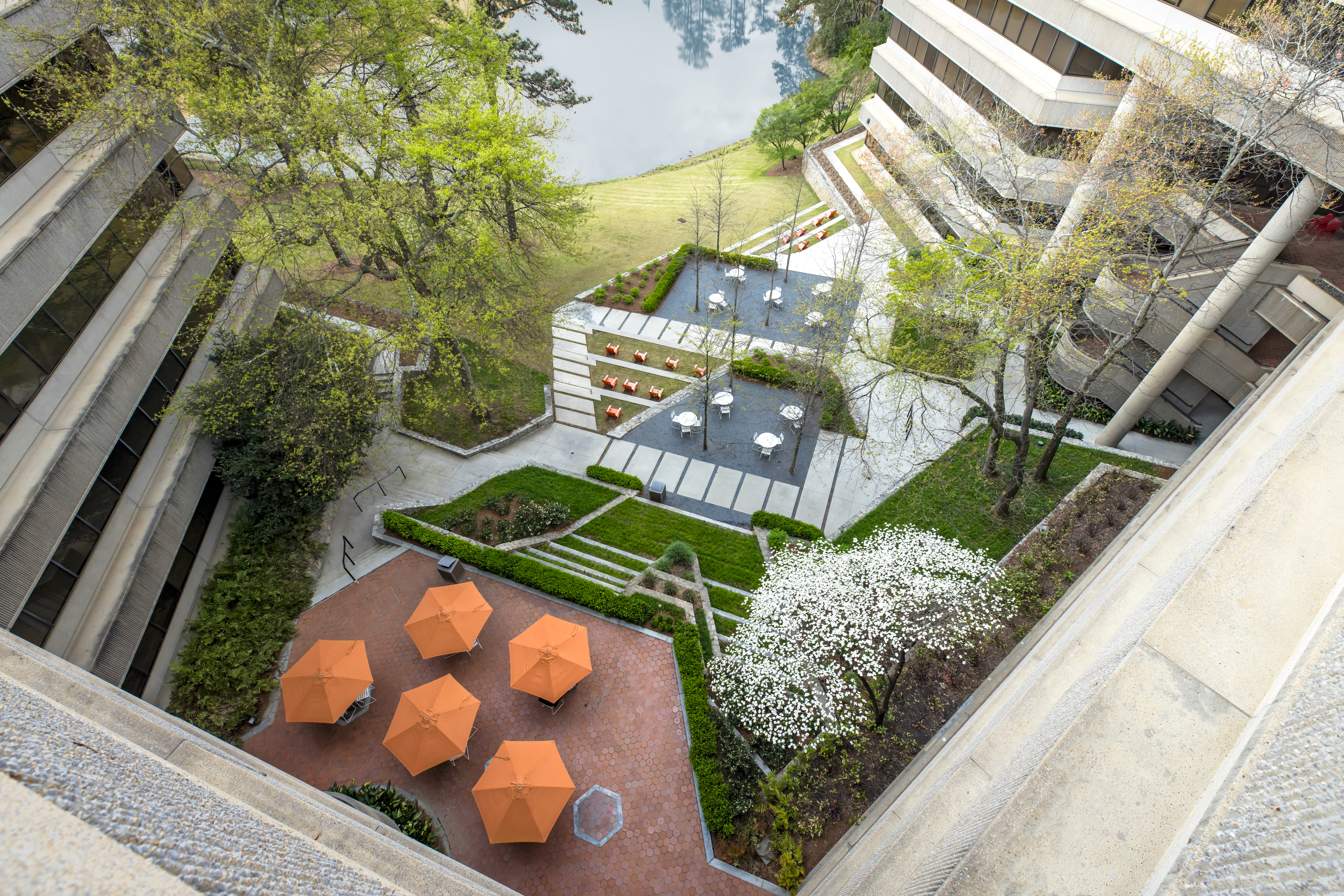 an aerial view of the Palisades courtyard shows lush green landscaping, an array of seating, and large orange umbrellas.